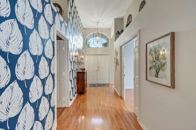 foyer featuring a textured ceiling, baseboards, wood finished floors, and an inviting chandelier