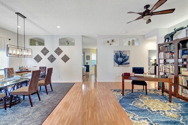 office featuring a textured ceiling, ceiling fan with notable chandelier, wood finished floors, and baseboards