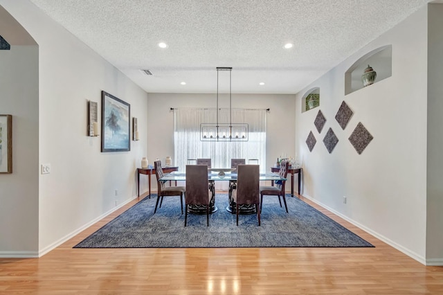 dining space featuring a textured ceiling, light wood finished floors, visible vents, and baseboards