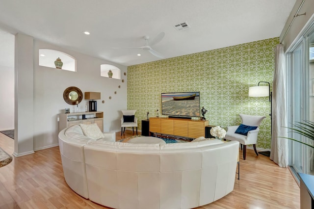 living room featuring baseboards, visible vents, light wood-style flooring, and wallpapered walls