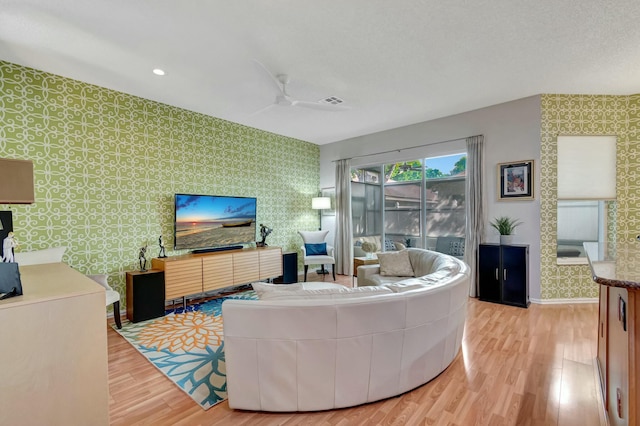 living room with wallpapered walls, ceiling fan, baseboards, and light wood finished floors