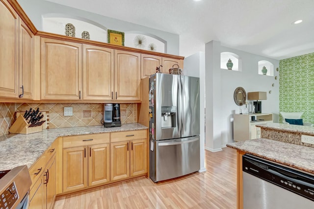 kitchen featuring stainless steel appliances, recessed lighting, decorative backsplash, light stone countertops, and light wood-type flooring