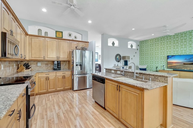 kitchen with ceiling fan, a kitchen island with sink, stainless steel appliances, a sink, and light wood-style floors