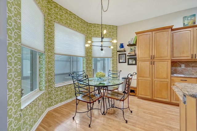 dining area featuring baseboards, light wood finished floors, and wallpapered walls