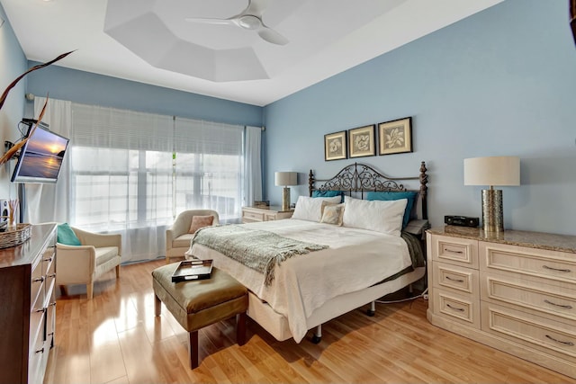 bedroom featuring light wood-style floors, a tray ceiling, and a ceiling fan
