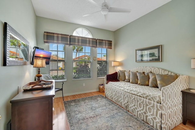 living area with a ceiling fan, light wood-type flooring, and baseboards