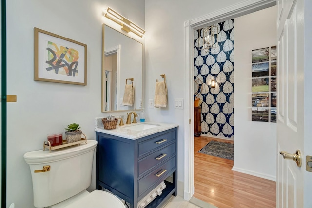 bathroom with toilet, baseboards, wood finished floors, and vanity
