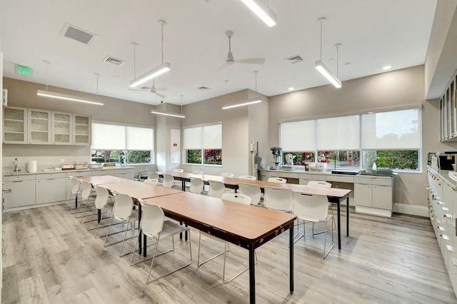 kitchen with glass insert cabinets, light countertops, light wood-type flooring, and visible vents