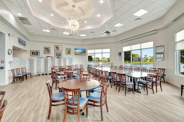 dining area featuring a high ceiling, visible vents, baseboards, light wood-style floors, and an inviting chandelier