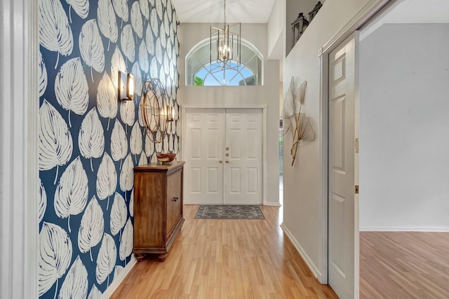 entrance foyer with a healthy amount of sunlight, baseboards, an inviting chandelier, and wood finished floors