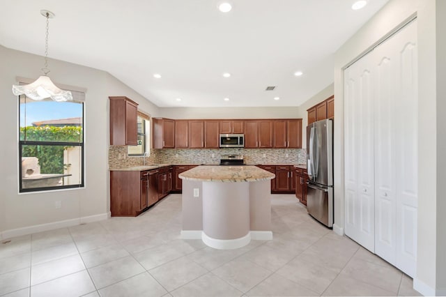 kitchen featuring appliances with stainless steel finishes, sink, backsplash, a kitchen island, and hanging light fixtures