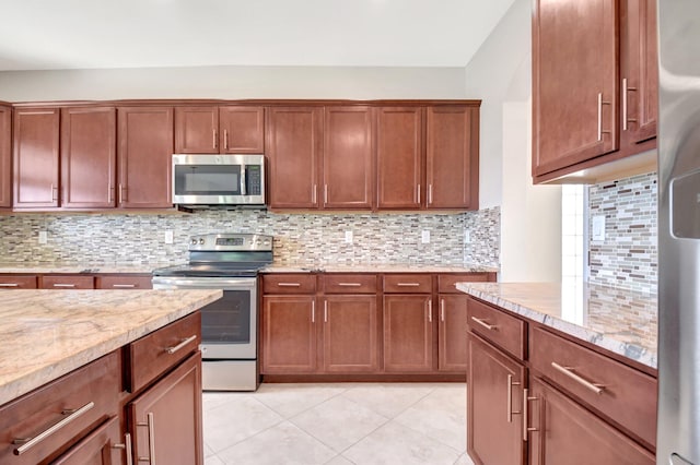 kitchen featuring appliances with stainless steel finishes, light stone countertops, backsplash, and light tile patterned floors