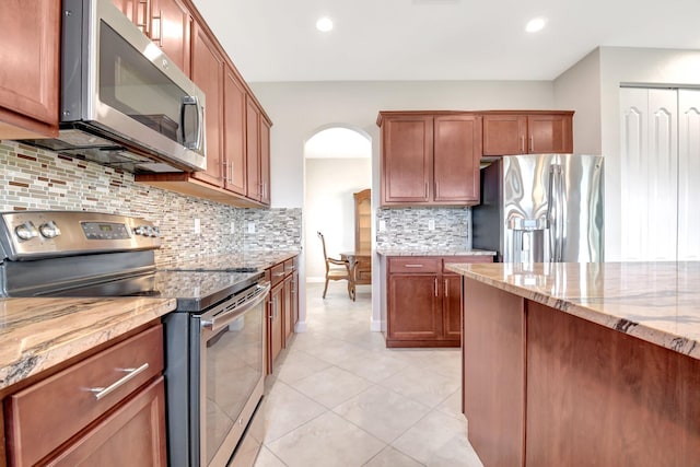 kitchen with decorative backsplash, light tile patterned flooring, stainless steel appliances, and light stone counters