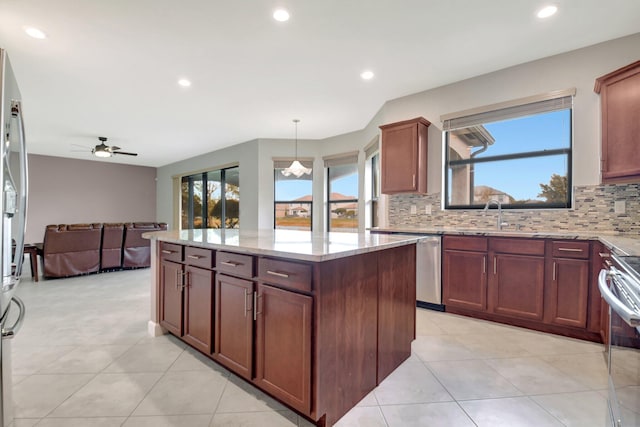 kitchen with sink, a center island, decorative light fixtures, stainless steel appliances, and light stone countertops