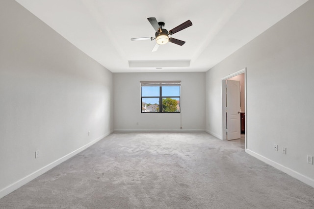 carpeted empty room with a tray ceiling and ceiling fan