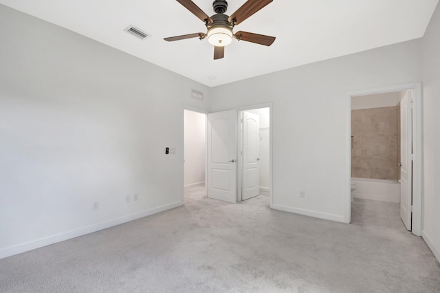 unfurnished bedroom featuring light carpet, connected bathroom, a closet, ceiling fan, and a spacious closet