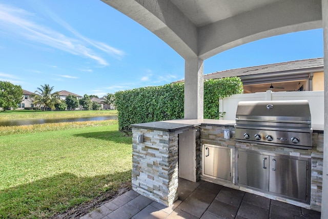 view of patio / terrace featuring a water view, exterior kitchen, and grilling area