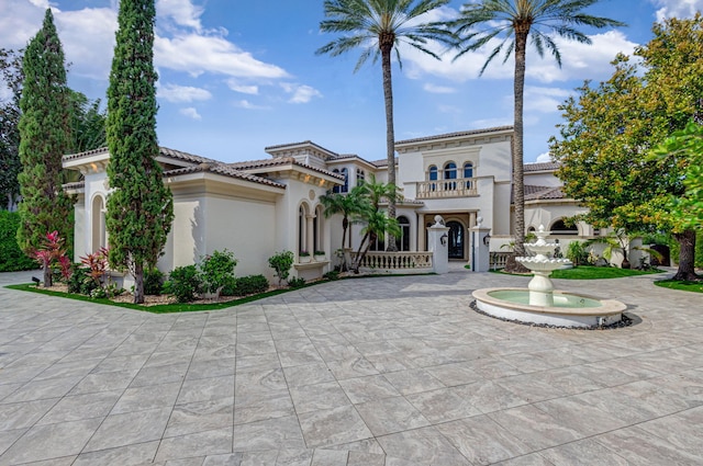 mediterranean / spanish-style house with a tile roof, a balcony, and stucco siding