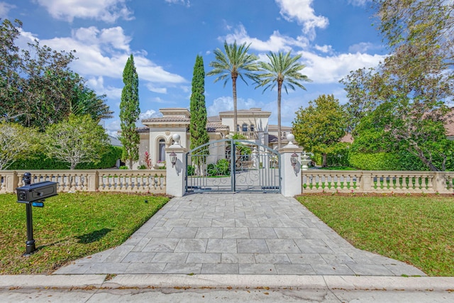 view of front facade with a fenced front yard, stucco siding, a gate, a tiled roof, and a front lawn