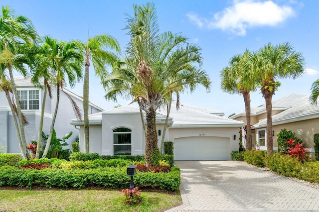 view of front facade featuring decorative driveway, a garage, and stucco siding