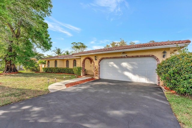 mediterranean / spanish-style house featuring a front yard and a garage