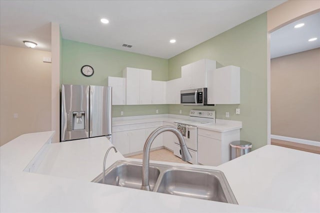 kitchen with appliances with stainless steel finishes, sink, and white cabinetry