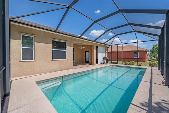 view of pool with a patio, ceiling fan, and glass enclosure