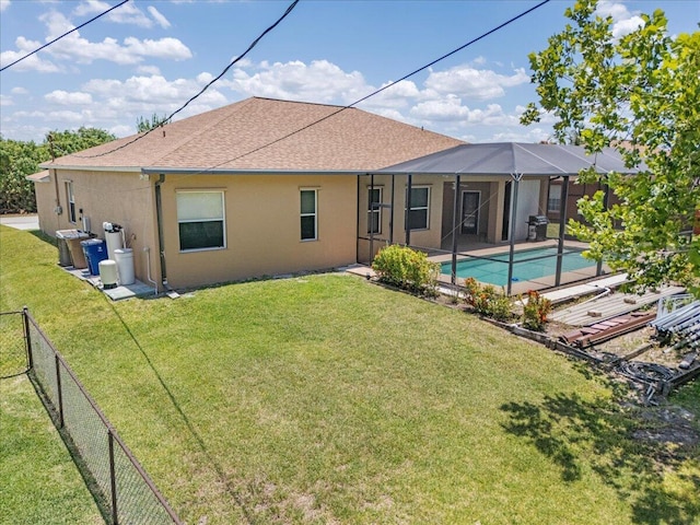 back of house featuring glass enclosure, a lawn, a fenced in pool, and a patio area