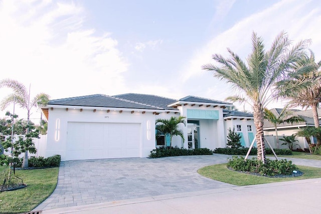 view of front of house featuring decorative driveway, an attached garage, and stucco siding