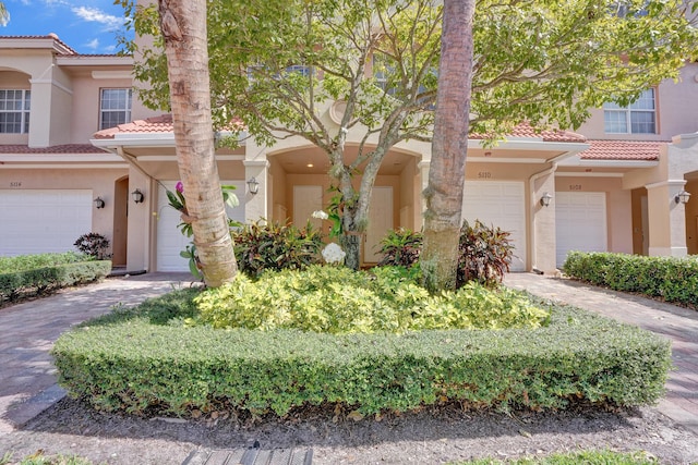 view of front of property featuring driveway, an attached garage, a tile roof, and stucco siding