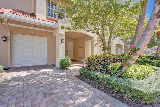 doorway to property with a tiled roof, decorative driveway, and stucco siding