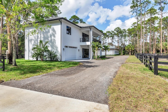 view of front of home featuring a garage, a balcony, and a front lawn