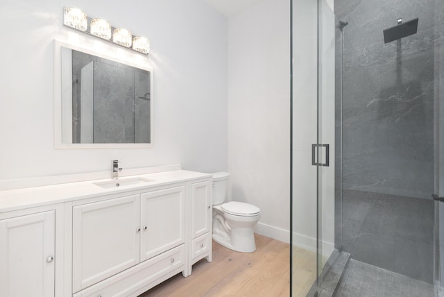 bathroom with toilet, vanity, wood-type flooring, and a shower with shower door