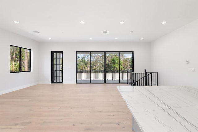 empty room with a healthy amount of sunlight and light hardwood / wood-style flooring