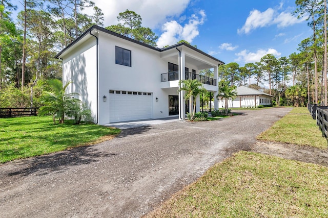 view of front of home with a front yard, a garage, and a balcony