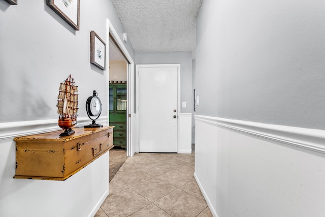 entryway with light tile patterned flooring and a textured ceiling