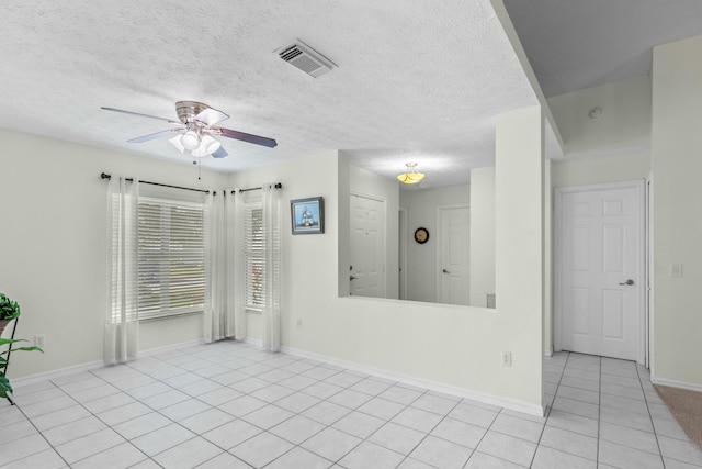 tiled spare room with ceiling fan and a textured ceiling