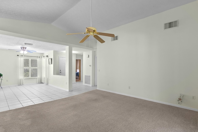 spare room featuring a textured ceiling, vaulted ceiling, ceiling fan, and light colored carpet