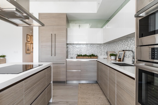 kitchen with stainless steel double oven, sink, tasteful backsplash, black electric stovetop, and island exhaust hood