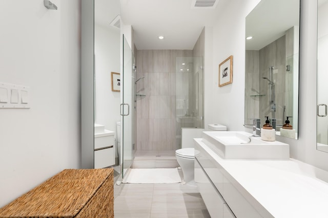 bathroom with vanity, a shower with door, toilet, and tile patterned floors