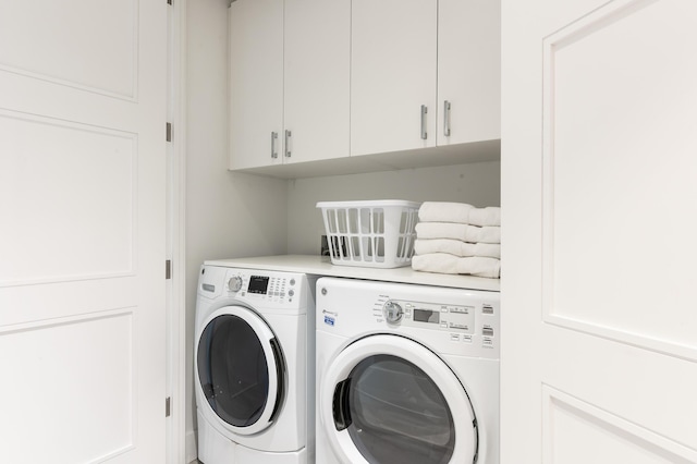 laundry room featuring washing machine and clothes dryer and cabinets