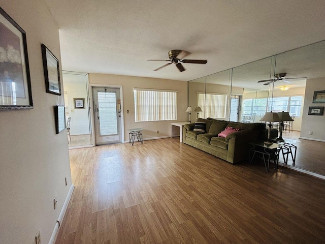 unfurnished living room featuring ceiling fan, baseboards, and wood finished floors