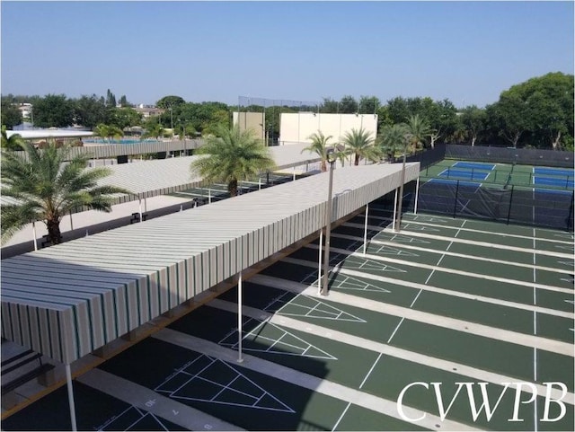 view of home's community with a tennis court, shuffleboard, and fence