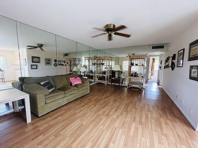 living area with visible vents, wood finished floors, a ceiling fan, and baseboards