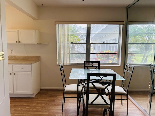 dining space featuring light wood-type flooring and baseboards