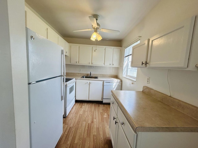 kitchen with light countertops, white appliances, a sink, and white cabinets