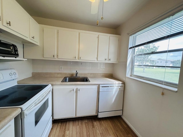 kitchen featuring light countertops, light wood-style flooring, white cabinetry, a sink, and white appliances