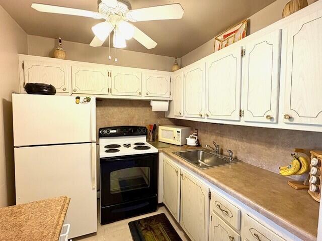 kitchen featuring decorative backsplash, white cabinets, a sink, ceiling fan, and white appliances