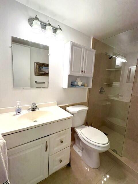 bathroom with tiled shower, vanity, toilet, and tile patterned floors