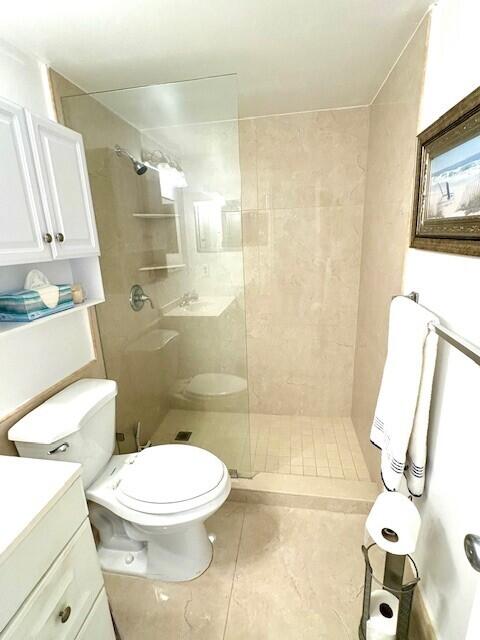 bathroom with toilet, tile patterned floors, a walk in shower, and vanity